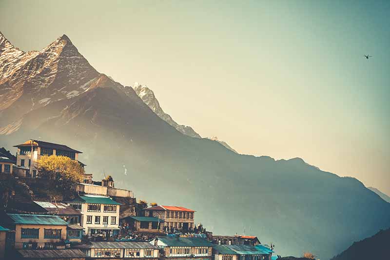A horizontal image of a view from Namche Bazaar, a village in Nepal with mountains in the background.