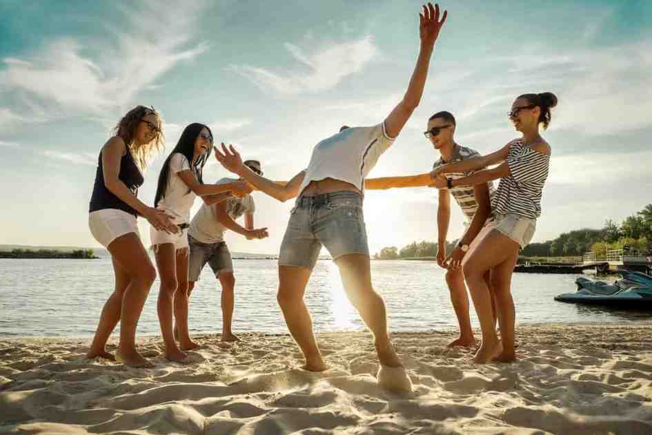 A group of adults enjoying a fun camping game on the beach during a sunny day.