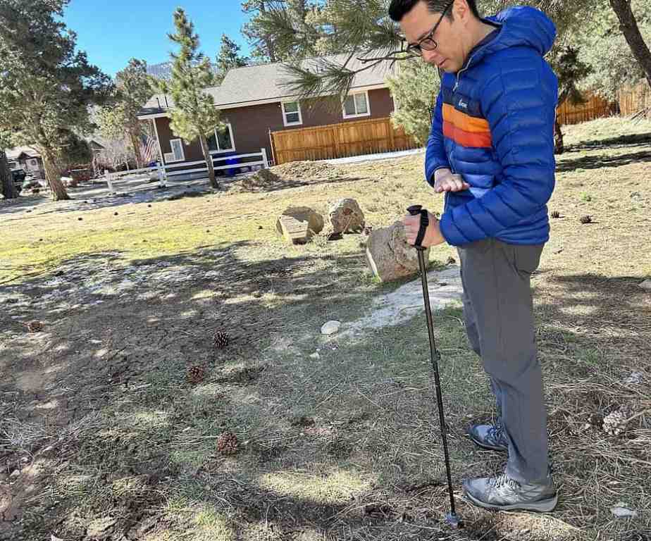 Hiker adjusting the length of trekking poles outdoors