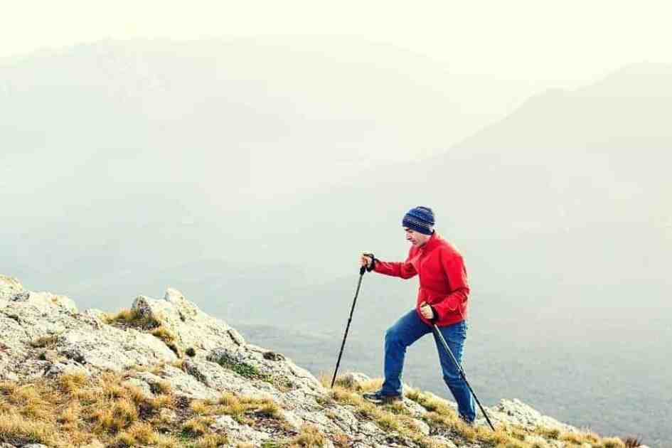 Hiker climbing a mountain using trekking poles for support