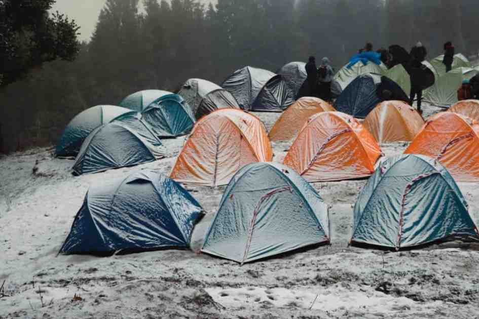 A group of tents covered in snow, showing the importance of weatherproofing for harsh conditions.