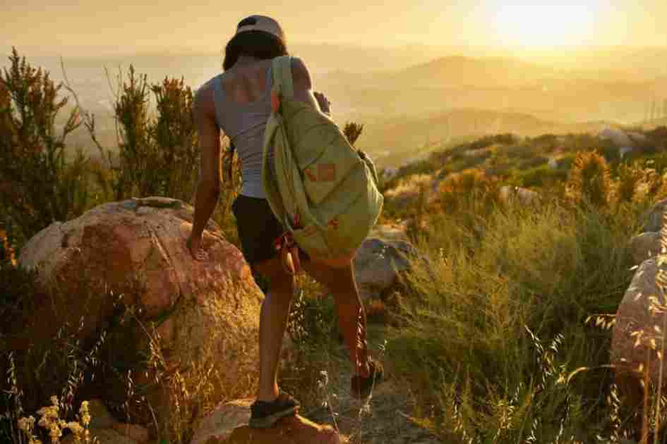 A woman hiking uphill at sunset, engaging major muscle groups like her legs, glutes, and core.