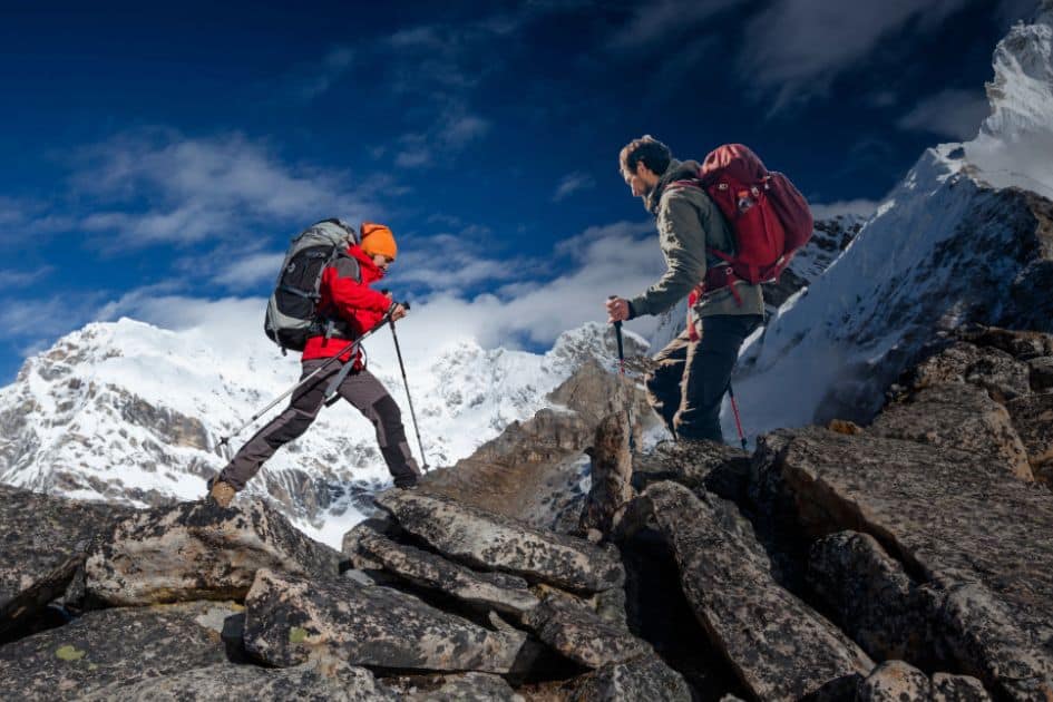 There's a hiker wearing rugged hiking pants climbing a rocky slope with a backpack. These pants are perfect for challenging terrains.